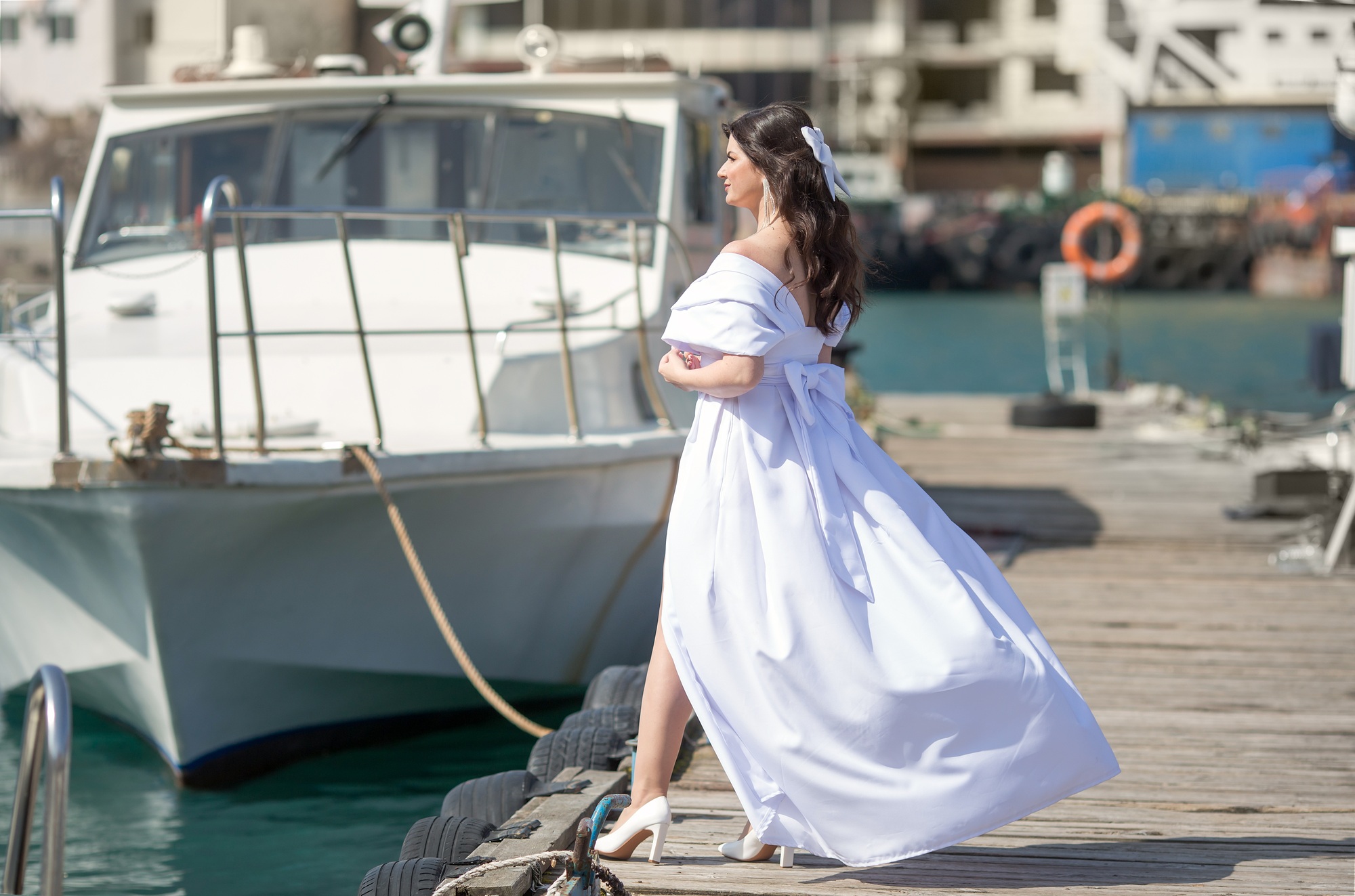 a girl in a wedding dress walking on the seashore at the berth.