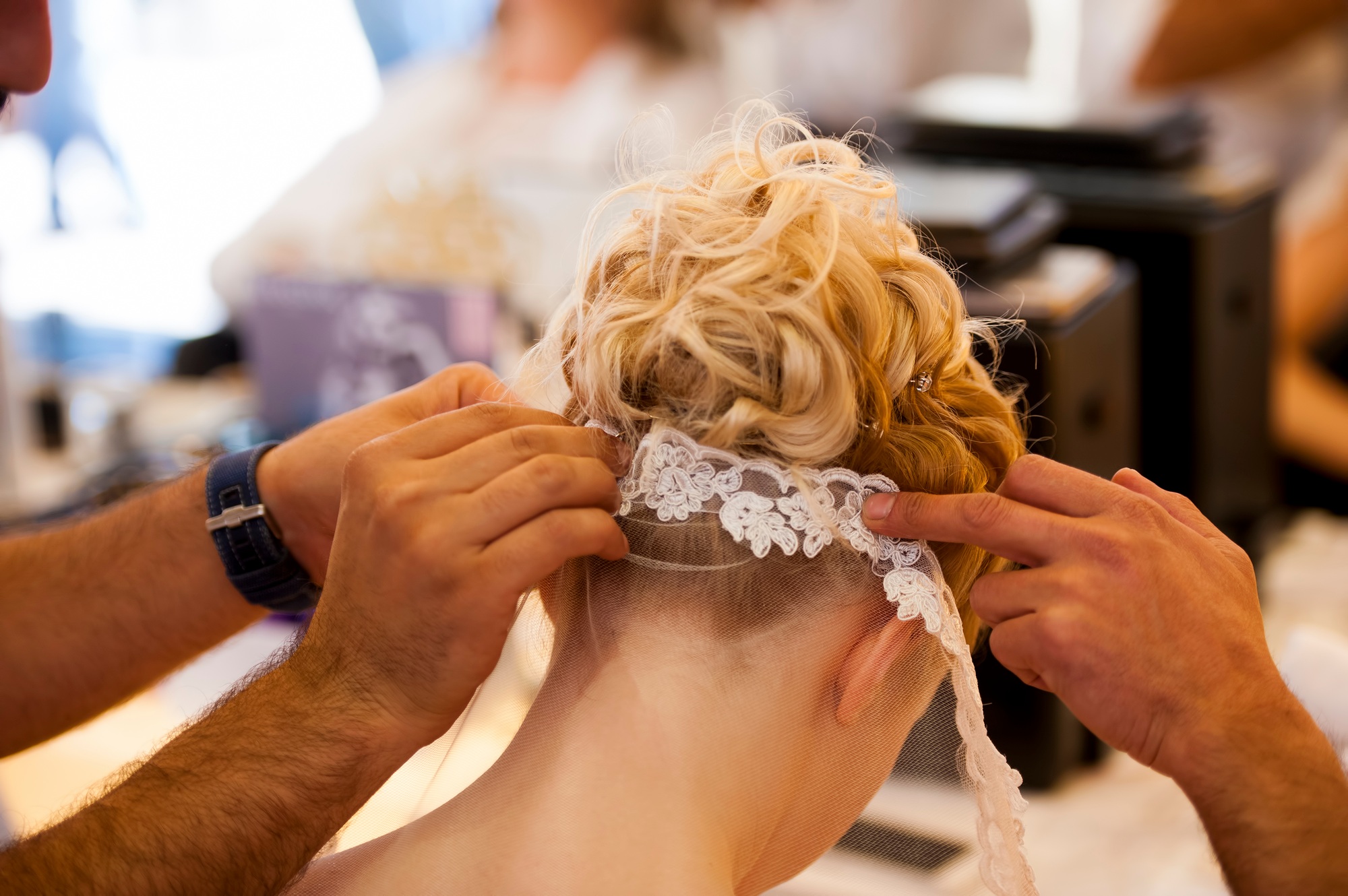 Hair stylist or florist makes the bride a wedding hairstyle
