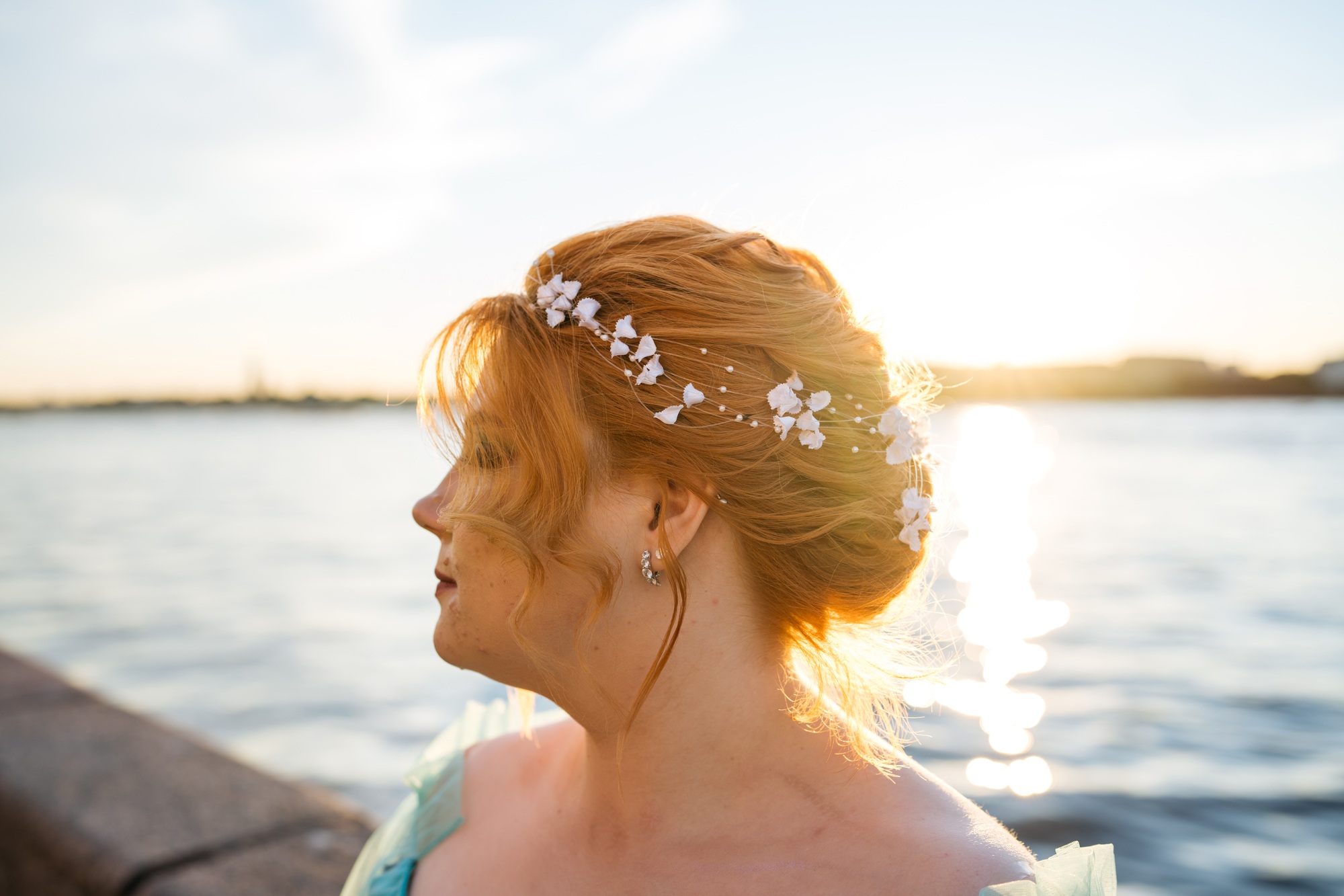 Portrait of young woman with red hair with wedding hairstyle with sunset backlight