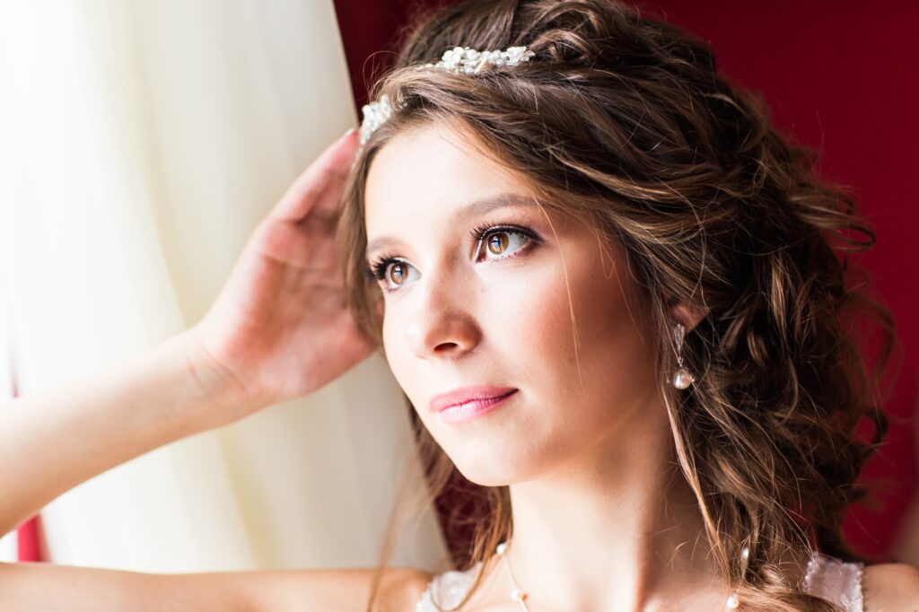 Beautiful young bride with wedding makeup and hairstyle in bedroom